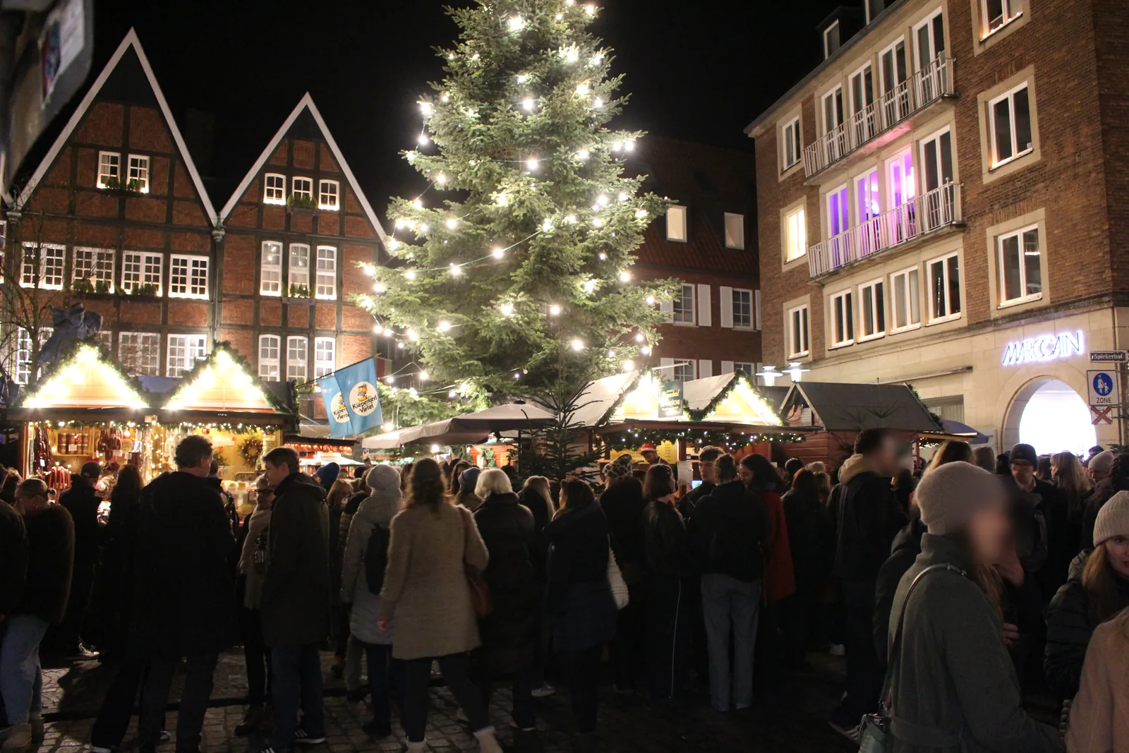 Kiepenkerl-Weihnachtsmarkt am Spiekerhof in Münster: beleuchtete Buden und eine große Weihnachtstanne zwischen Fachwerkgiebeln.