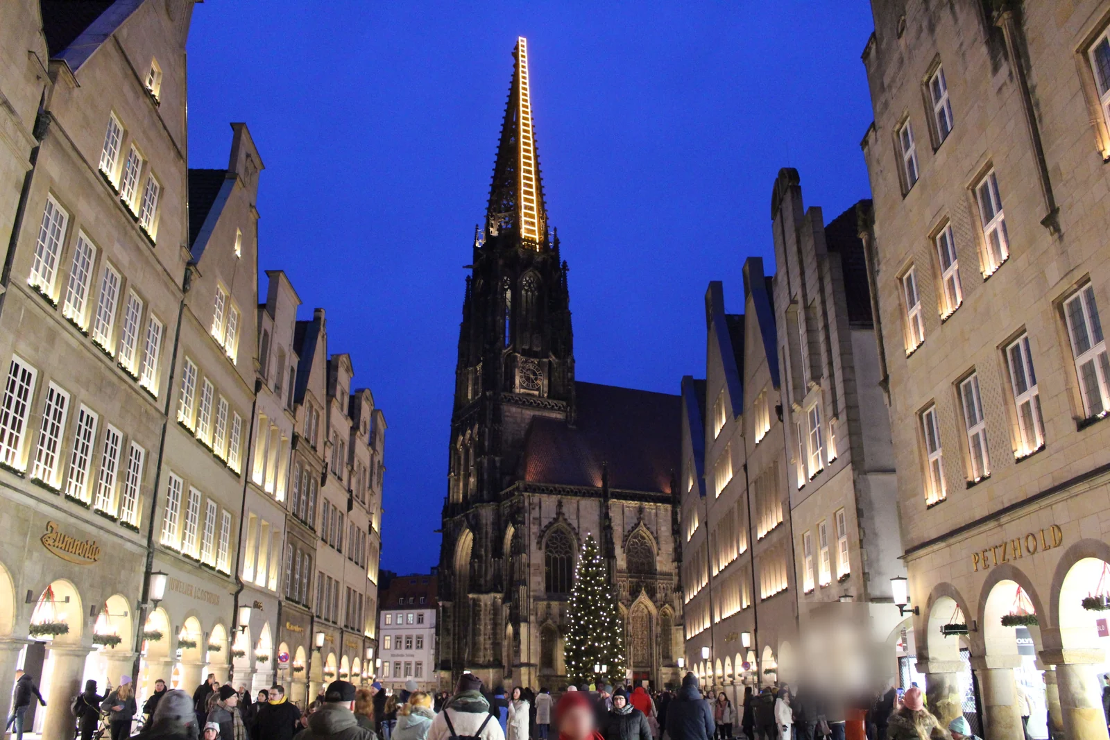Prinzipalmarkt Münster zur blauen Stunde: die golden beleuchtete Lichtinstallation Himmelsleiter am Turm von St. Lamberti über dem Weihnachtsmarkt und der großen Weihnachtstanne.